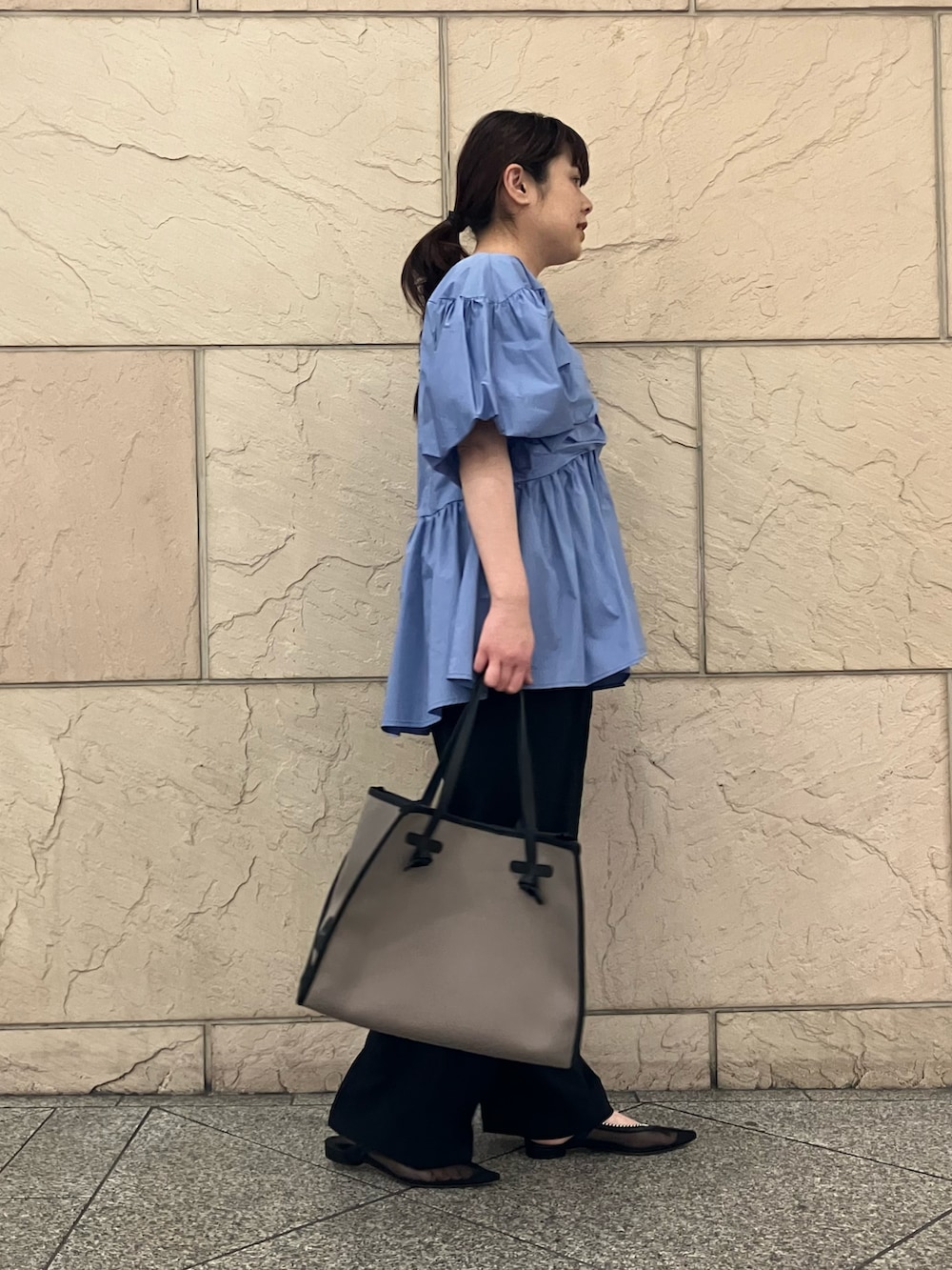 ブルー系のシャツ/ブラウス、ブラック系のその他パンツ、グレー系のバッグを着用したレディースの春コーディネートの2枚目の写真