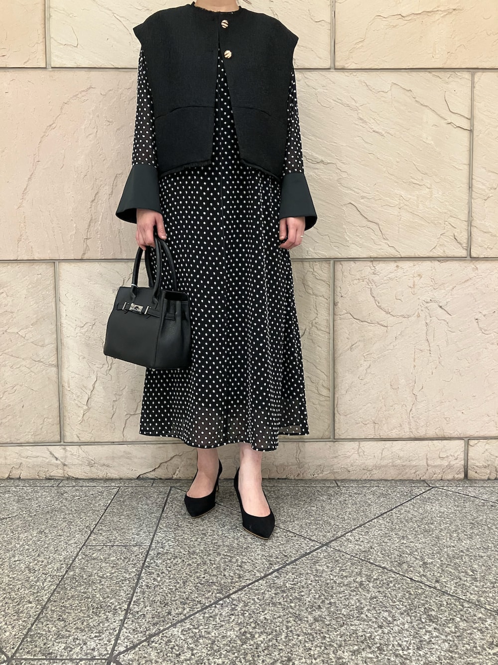 ブラック系のベスト、ブラック系のワンピース、ブラック系のパンプスを着用したレディースの秋コーディネートの5枚目の写真