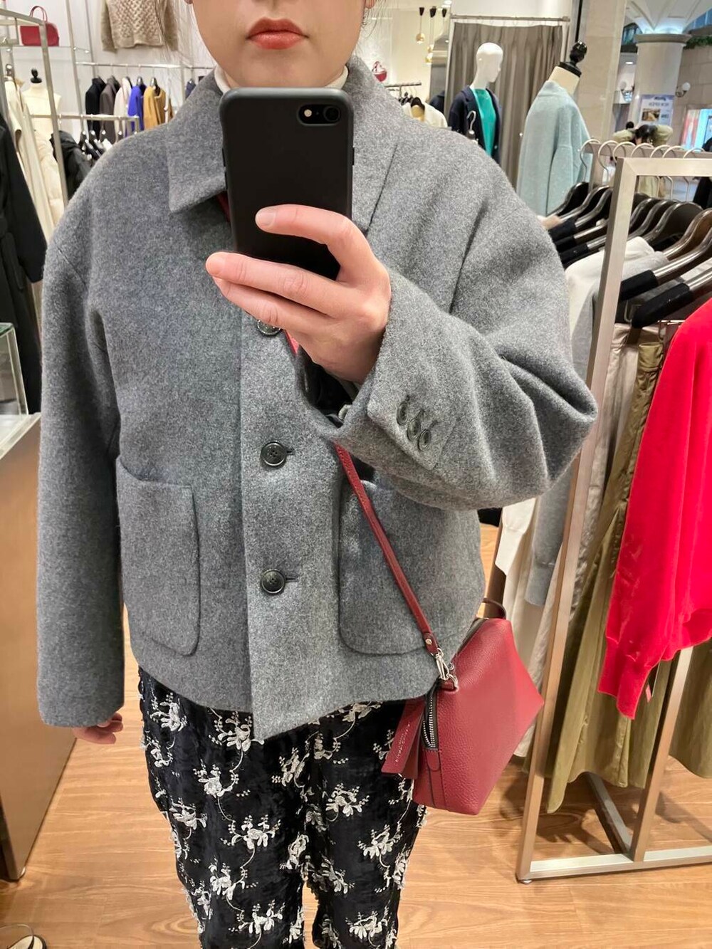 ホワイト系のニット/セーター、グレー系のその他アウター、レッド系のショルダーバッグを着用したレディースの冬コーディネートの3枚目の写真