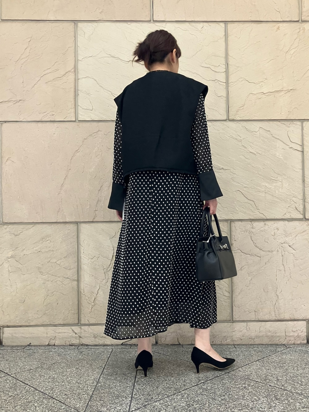 ブラック系のベスト、ブラック系のワンピース、ブラック系のパンプスを着用したレディースの秋コーディネートの3枚目の写真