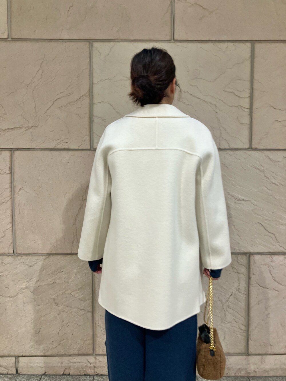 ホワイト系のチェスターコート、ブルー系のワンピース、ブラック系のブーツを着用したレディースの冬コーディネートの3枚目の写真