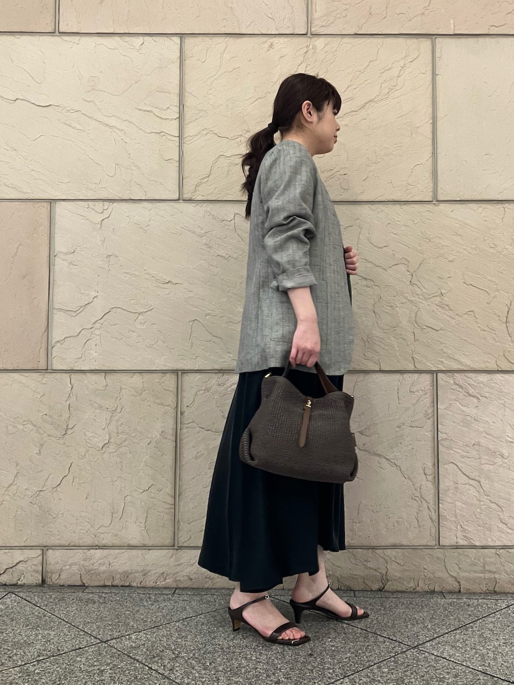 ブラウン系のタンクトップ、グレー系のノーカラージャケット、ブラック系のワンピースを着用したレディースの春コーディネートの2枚目の写真