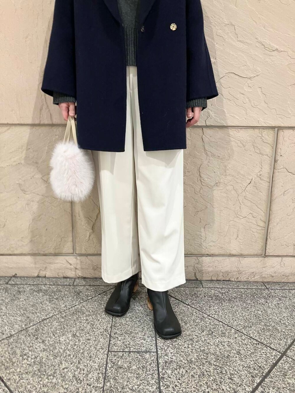 グレー系のニット/セーター、ブルー系のチェスターコート、ホワイト系のその他パンツを着用したレディースの冬コーディネートの5枚目の写真