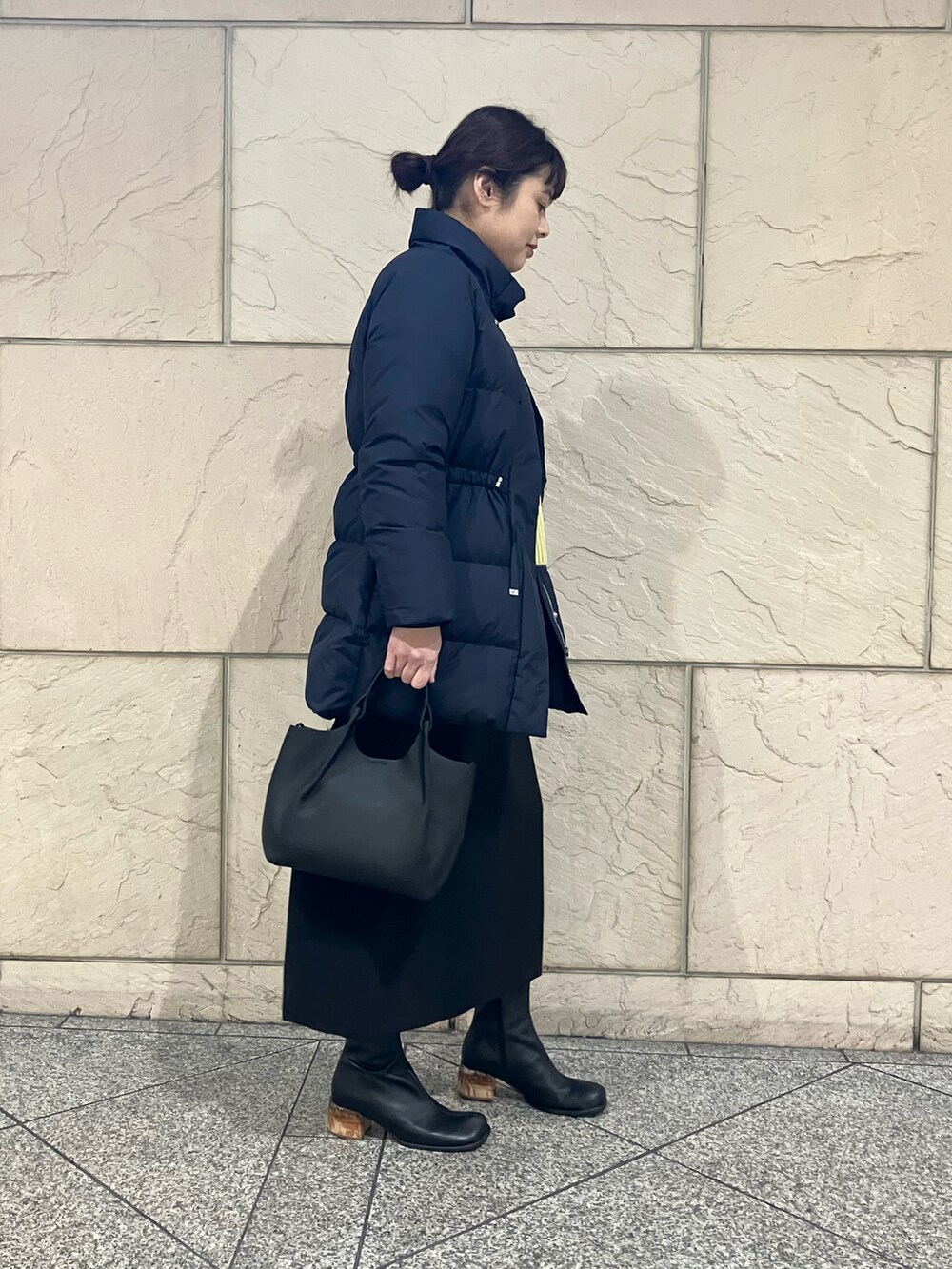 ブルー系のダウンジャケット/コート、イエロー系のニット/セーター、ブラック系のスカートを着用したレディースの冬コーディネートの2枚目の写真