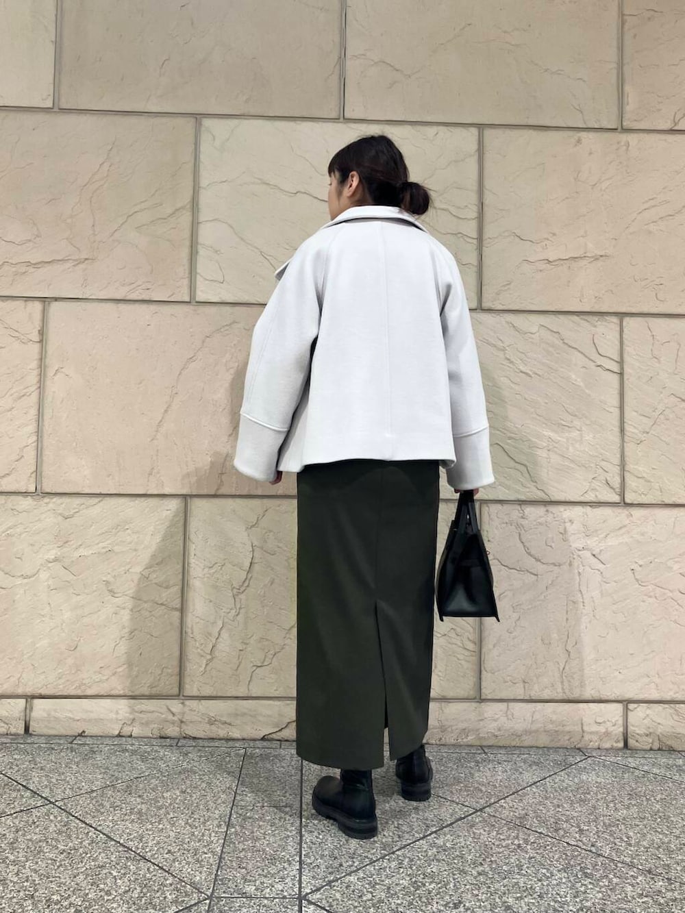 グリーン系のスカート、グレー系のピーコート、ブラック系のブーツを着用したレディースの冬コーディネートの3枚目の写真