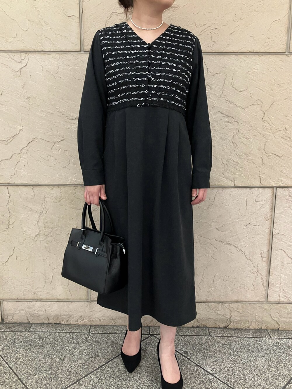 ブラック系のワンピース、ブラック系のパンプス、ブラック系のハンドバッグを着用したレディースの秋コーディネートの4枚目の写真