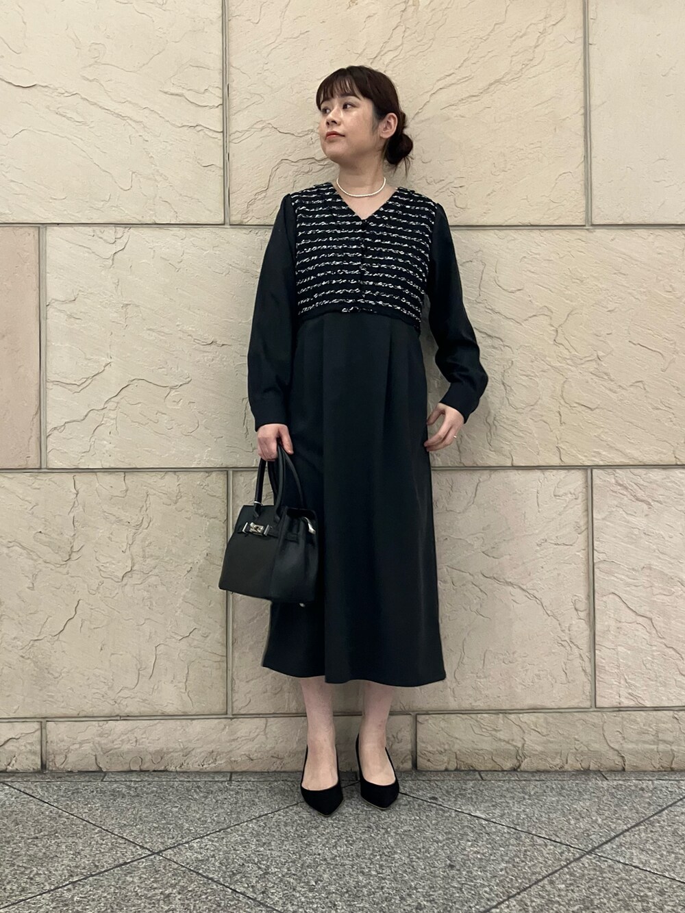 ブラック系のワンピース、ブラック系のパンプス、ブラック系のハンドバッグを着用したレディースの秋コーディネートの5枚目の写真