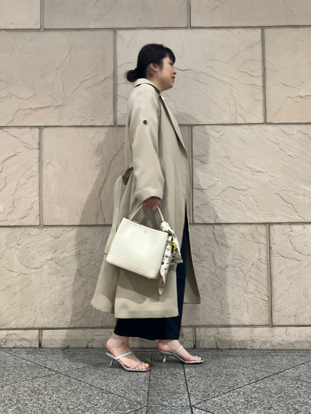 ベージュ系のトレンチコート、イエロー系のカーディガン/ボレロ、グレー系のその他パンツを着用したレディースの冬コーディネートの2枚目の写真