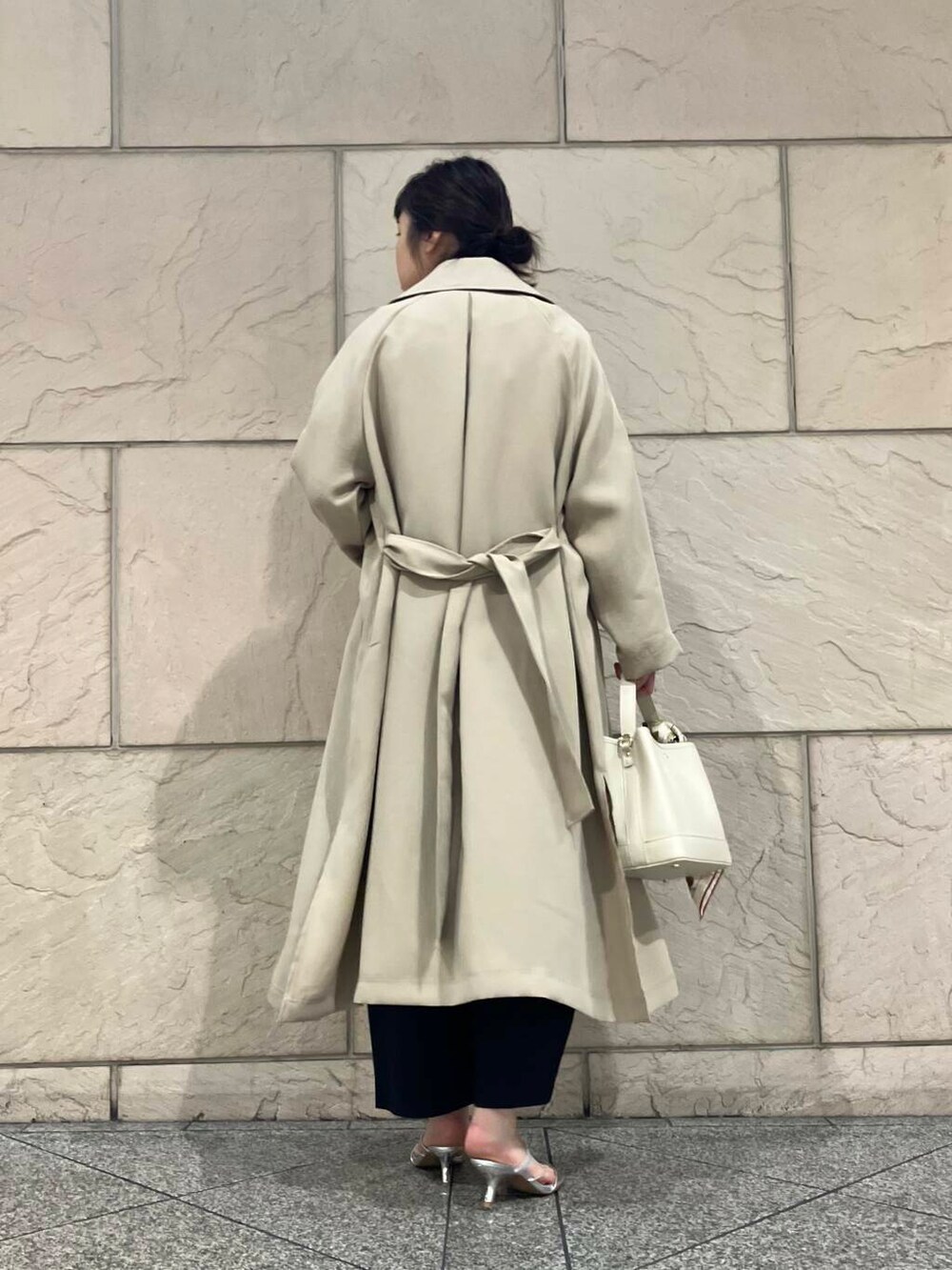 ベージュ系のトレンチコート、イエロー系のカーディガン/ボレロ、グレー系のその他パンツを着用したレディースの冬コーディネートの3枚目の写真