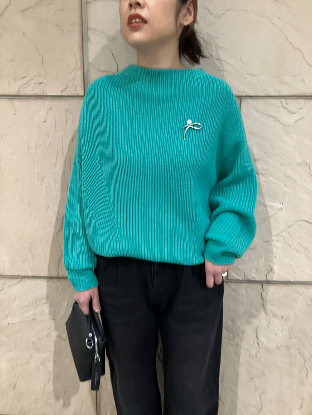 グリーン系のニット/セーター、ブラック系のデニムパンツ、ブラック系のショルダーバッグを着用したレディースの冬コーディネートの4枚目の写真