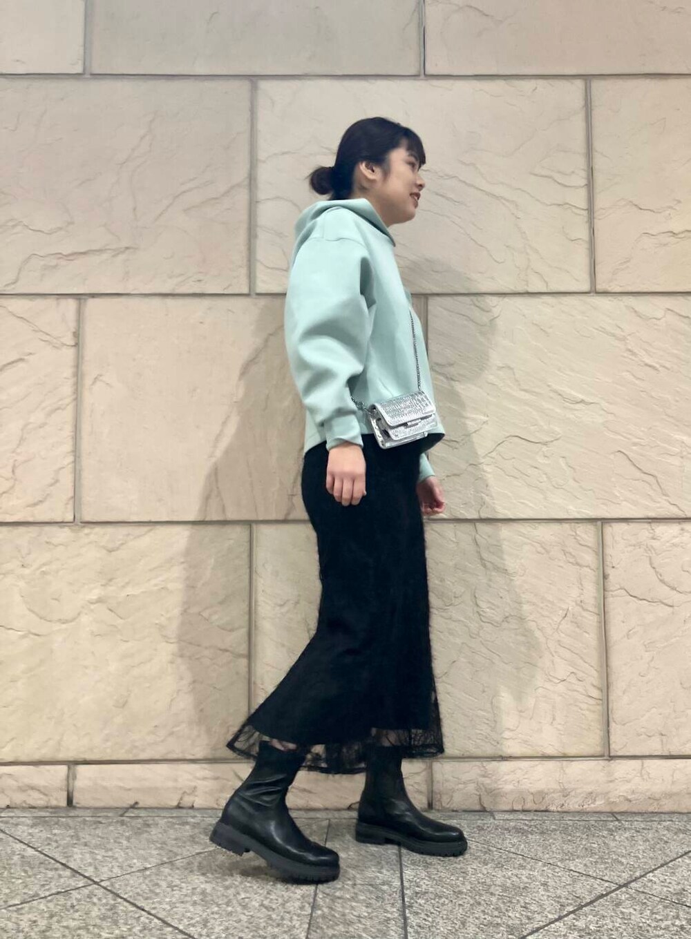 ブラック系のブーツ、シルバー系のショルダーバッグ、ブラック系のスカートを着用したレディースの冬コーディネートの2枚目の写真