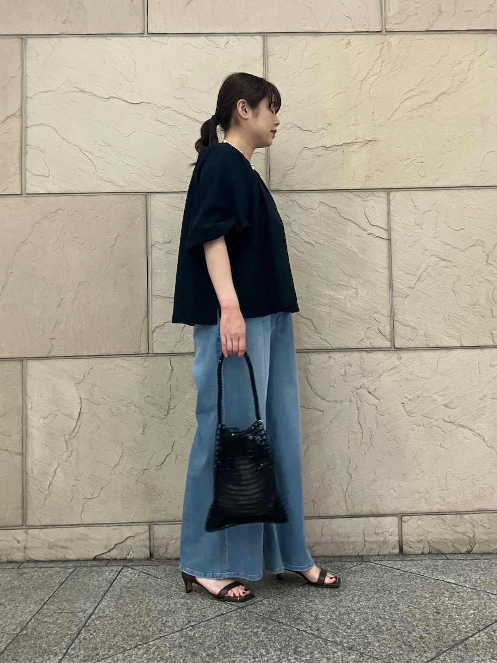 ブルー系のシャツ/ブラウス、ブラック系のハンドバッグ、ブルー系のデニムパンツを着用したレディースの夏コーディネートの2枚目の写真