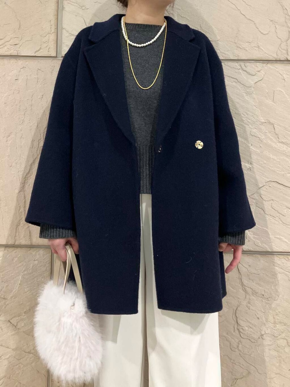 グレー系のニット/セーター、ブルー系のチェスターコート、ホワイト系のその他パンツを着用したレディースの冬コーディネートの4枚目の写真