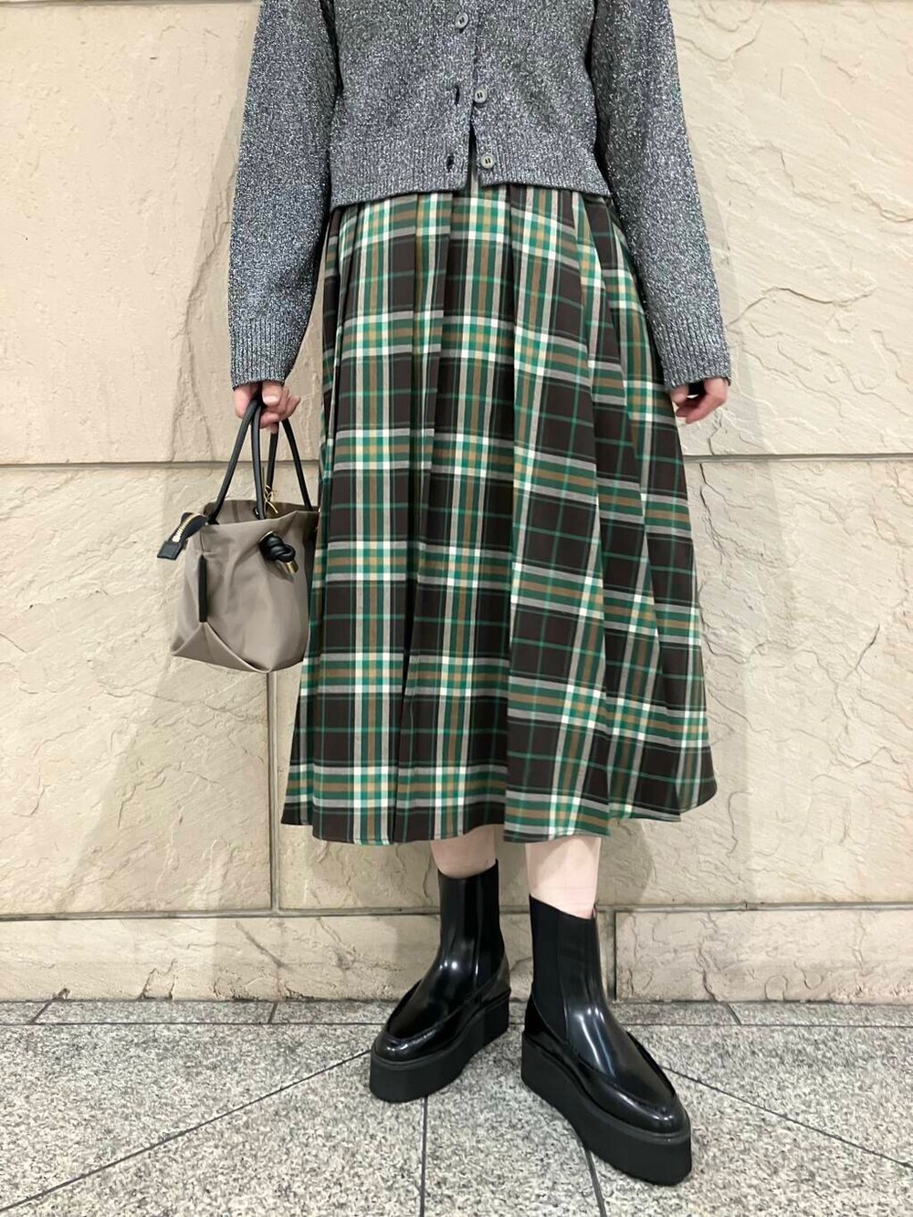 ベージュ系のハンドバッグ、ブラック系のニット/セーター、グリーン系のスカートを着用したレディースの秋コーディネートの4枚目の写真