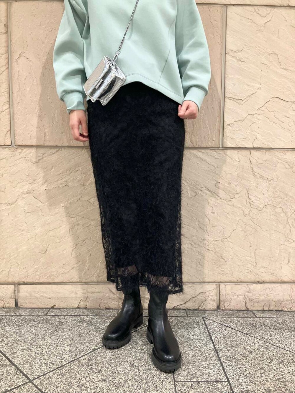 ブラック系のブーツ、シルバー系のショルダーバッグ、ブラック系のスカートを着用したレディースの冬コーディネートの4枚目の写真