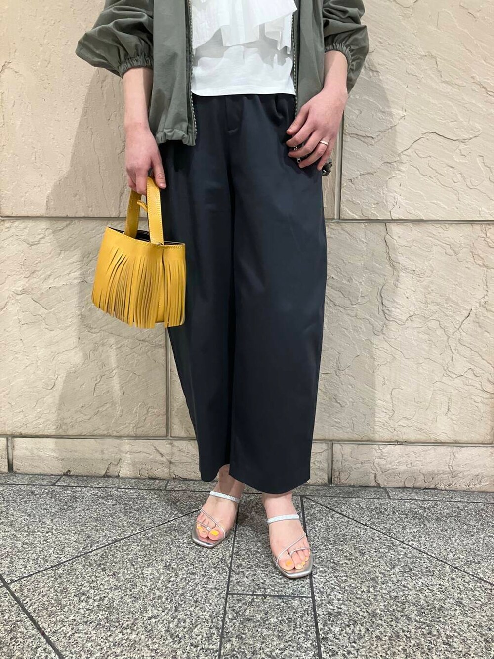 グリーン系のブルゾン、グレー系のその他パンツ、イエロー系のハンドバッグを着用したレディースの春コーディネートの5枚目の写真