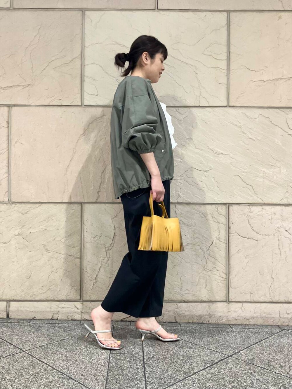 グリーン系のブルゾン、グレー系のその他パンツ、イエロー系のハンドバッグを着用したレディースの春コーディネートの2枚目の写真