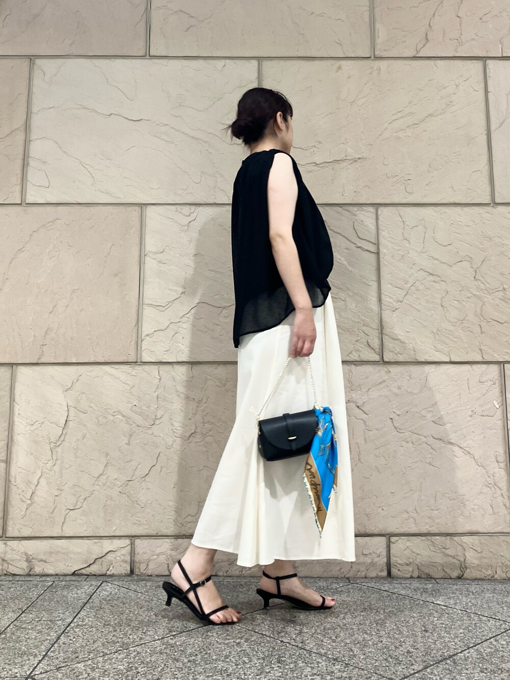 ブラック系のシャツ/ブラウス、ホワイト系のスカート、ブラック系のサンダルを着用したレディースの夏コーディネートの2枚目の写真