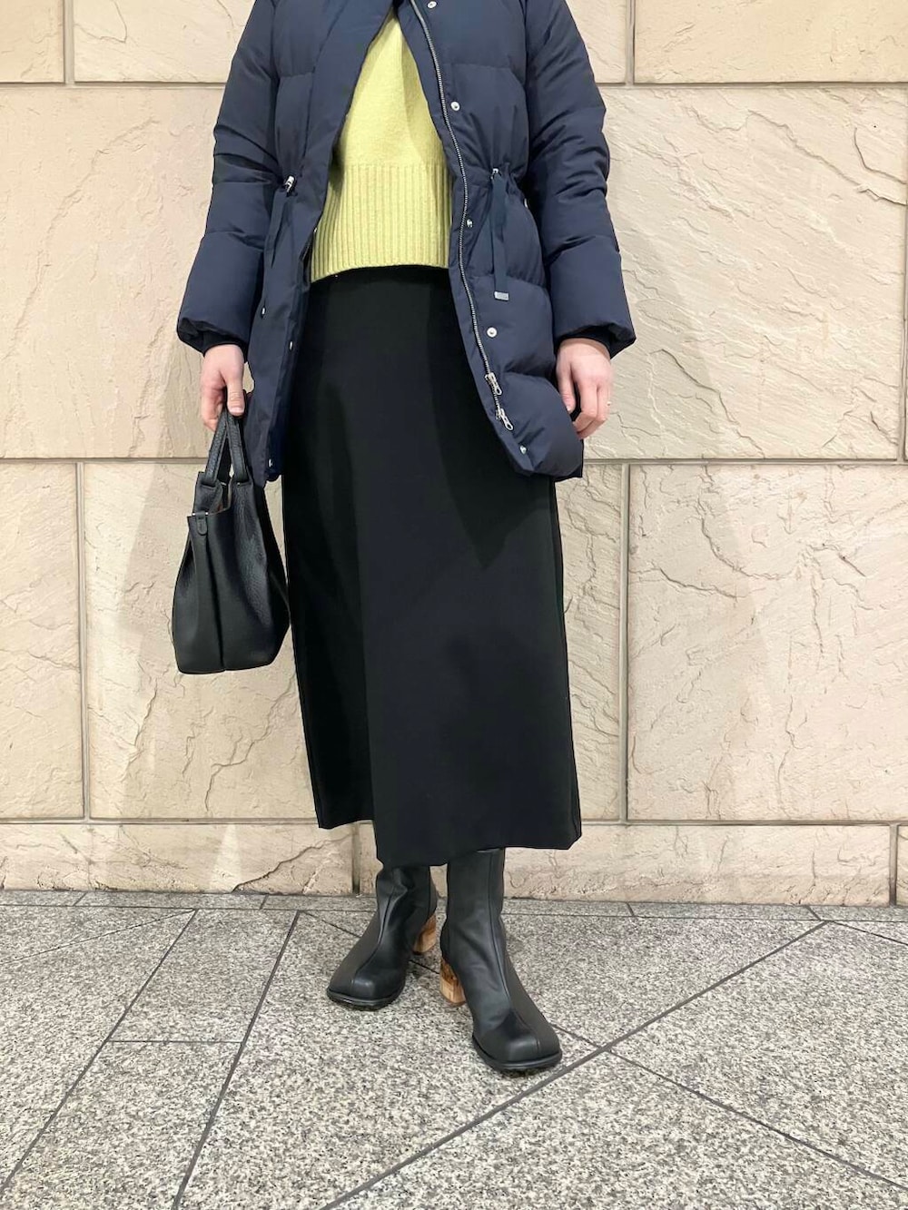 イエロー系のニット/セーター、ブラック系のスカート、ブルー系のダウンジャケット/コートを着用したレディースの冬コーディネートの5枚目の写真