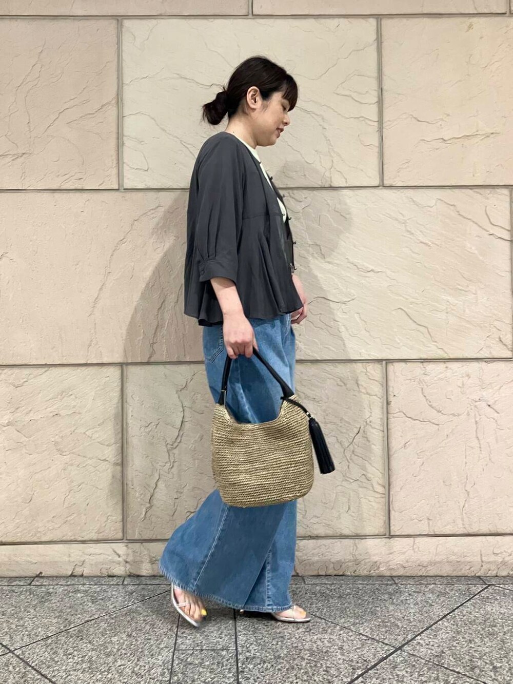 ブラウン系のかごバッグ、グリーン系のTシャツ/カットソー、ブルー系のデニムパンツを着用したレディースの夏コーディネートの2枚目の写真