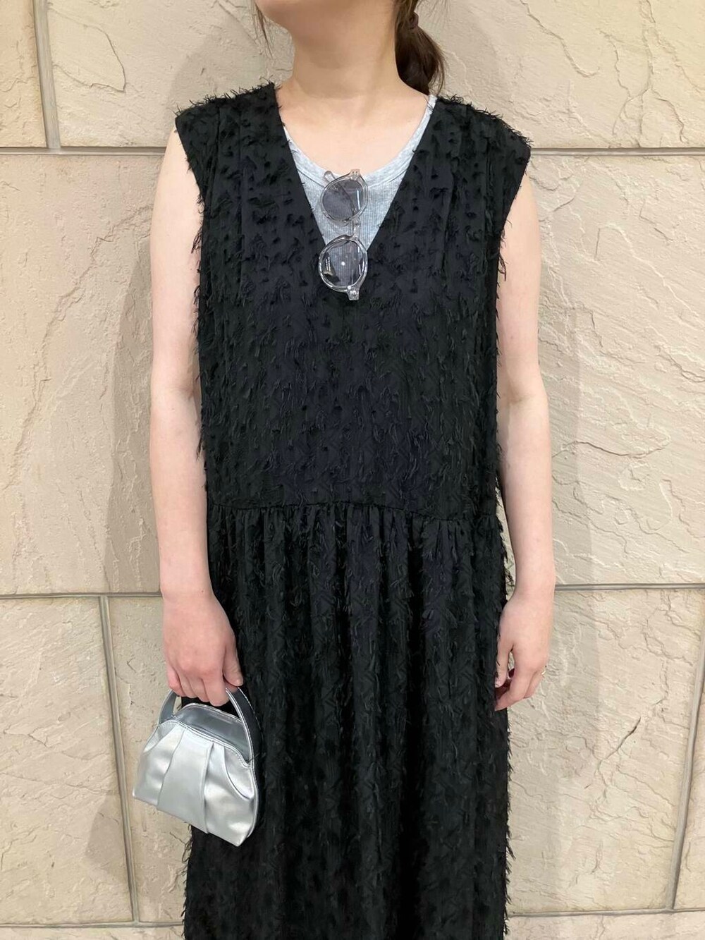 シルバー系のハンドバッグ、ブラック系のワンピース、その他のメガネを着用したレディースの夏コーディネートの3枚目の写真