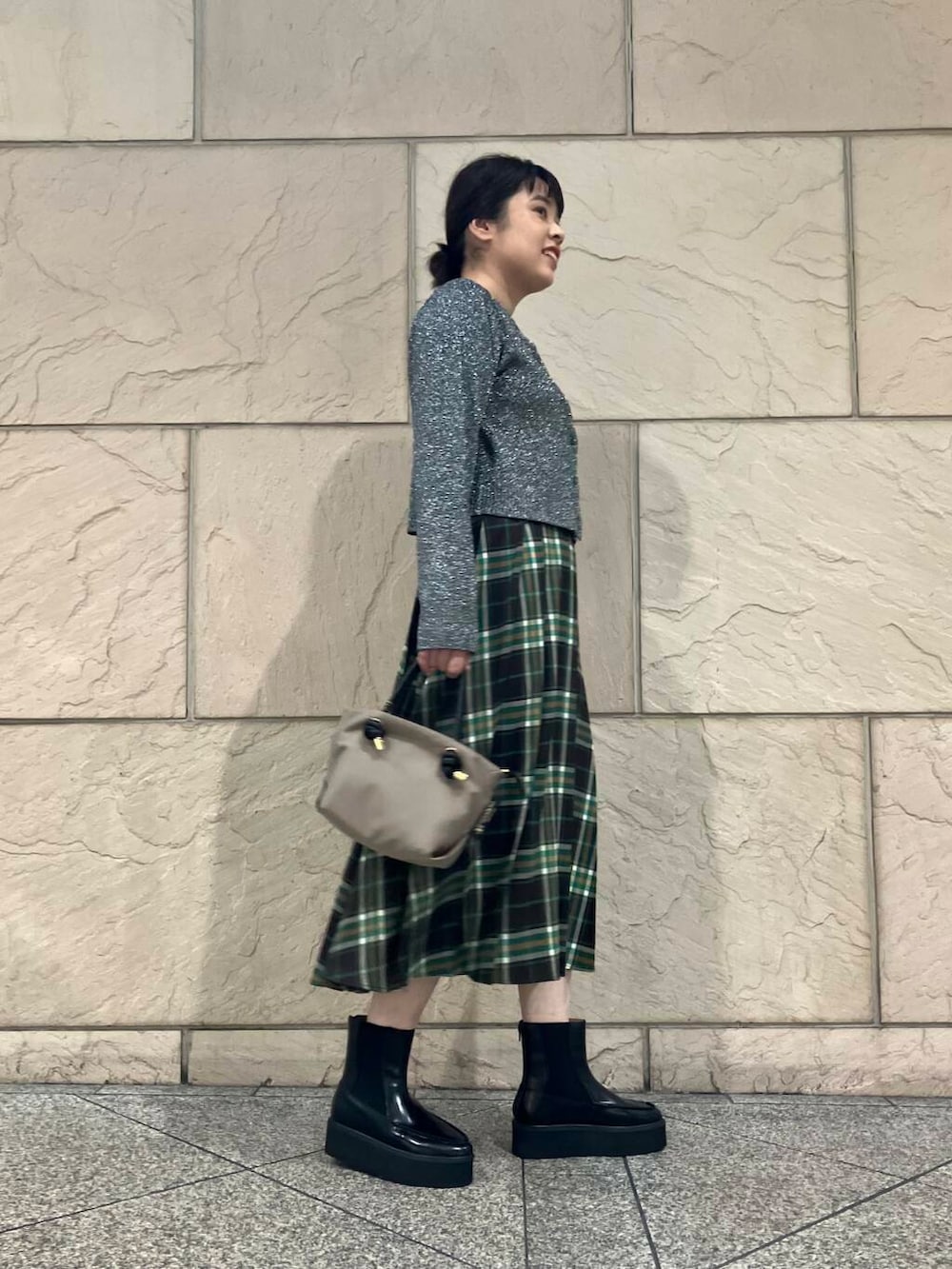 ベージュ系のハンドバッグ、ブラック系のニット/セーター、グリーン系のスカートを着用したレディースの秋コーディネートの2枚目の写真