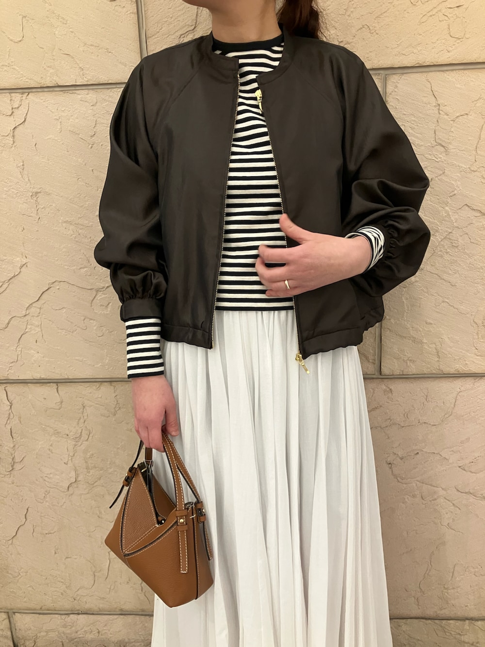 ホワイト系のTシャツ/カットソー、ブラウン系のブルゾン、ホワイト系のスカートを着用したレディースの春コーディネートの4枚目の写真