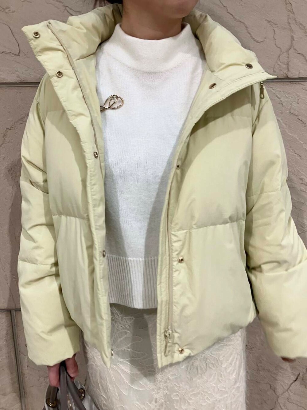 ブラック系のブーツ、イエロー系のダウンジャケット/コート、ホワイト系のスカートを着用したレディースの冬コーディネートの4枚目の写真