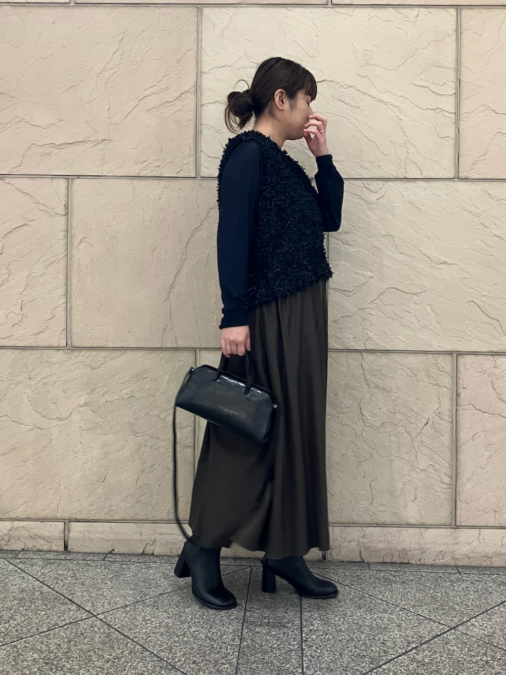 ブルー系のTシャツ/カットソー、ブラック系のベスト、ブラウン系のスカートを着用したレディースの秋コーディネートの2枚目の写真