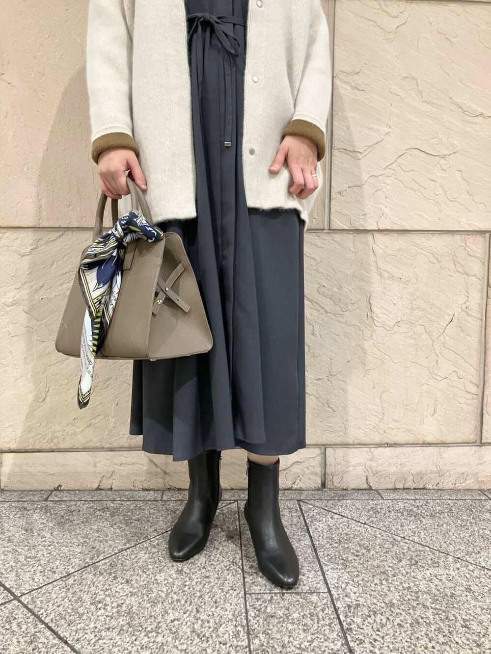 グレー系のワンピース、グレー系のカーディガン/ボレロ、ブラック系のブーツを着用したレディースの秋コーディネートの2枚目の写真