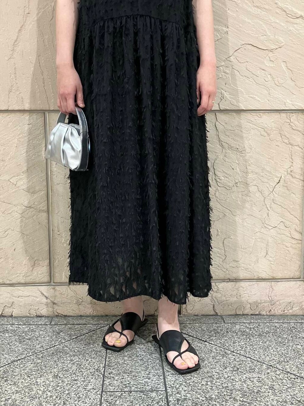 シルバー系のハンドバッグ、ブラック系のワンピース、その他のメガネを着用したレディースの夏コーディネートの4枚目の写真