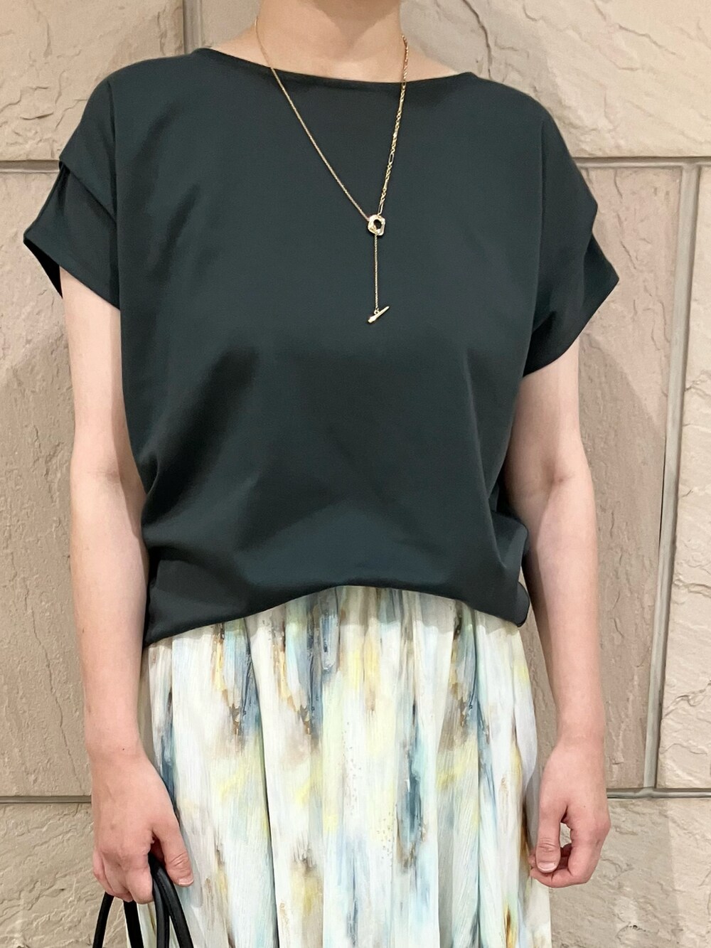 グリーン系のTシャツ/カットソー、ホワイト系のスカート、ベージュ系のトートバッグを着用したレディースの夏コーディネートの4枚目の写真