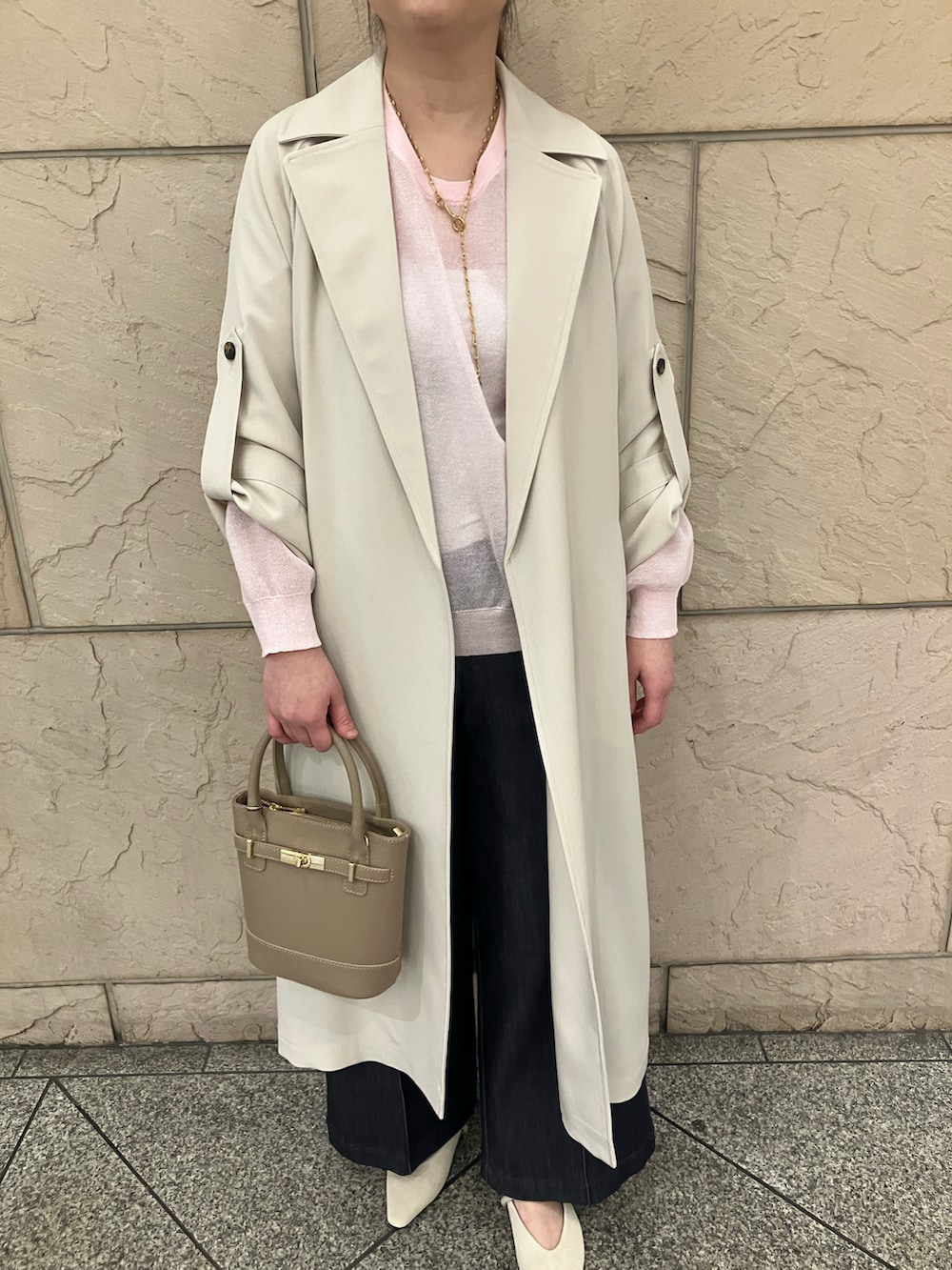 ピンク系のニット/セーター、ホワイト系のトレンチコート、ブルー系のデニムパンツを着用したレディースの春コーディネートの4枚目の写真