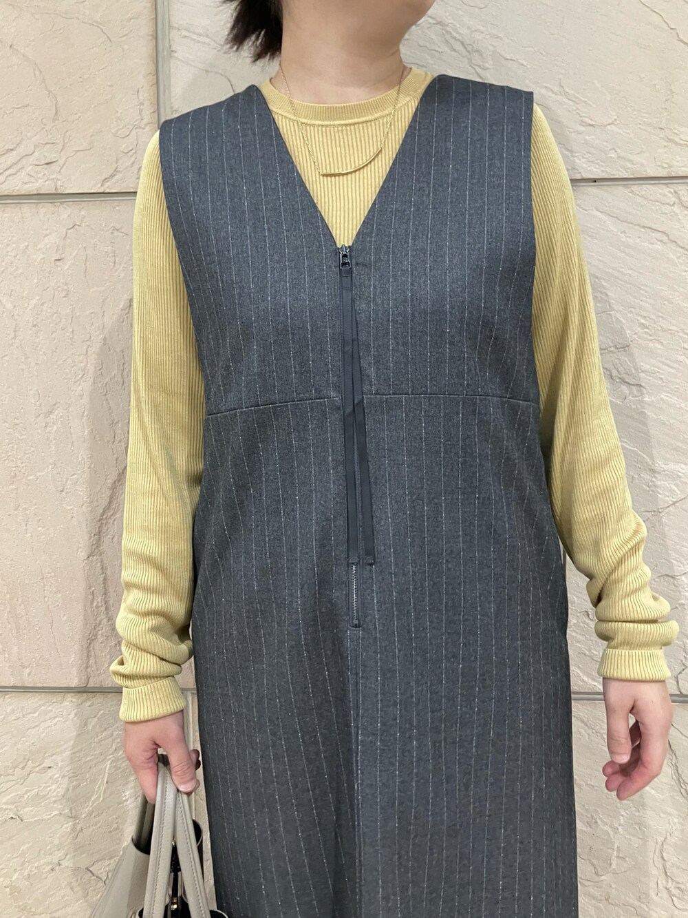 グレー系のワンピース、イエロー系のニット/セーター、ベージュ系のトートバッグを着用したレディースの秋コーディネートの4枚目の写真