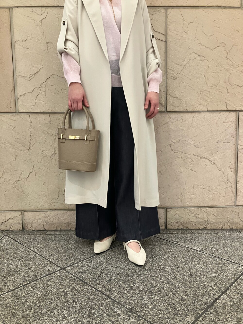 ピンク系のニット/セーター、ホワイト系のトレンチコート、ブルー系のデニムパンツを着用したレディースの春コーディネートの5枚目の写真