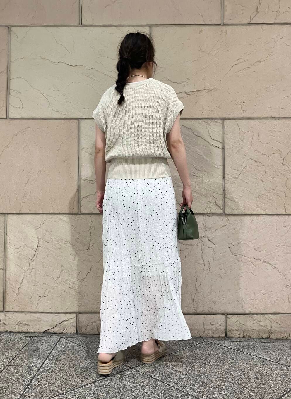 ベージュ系のベスト、ホワイト系のスカート、シルバー系のネックレスを着用したレディースの夏コーディネートの3枚目の写真