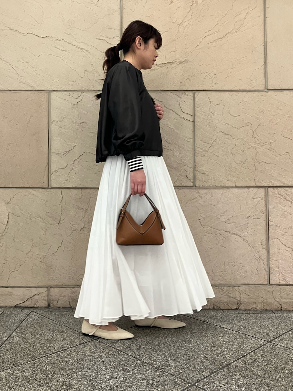 ホワイト系のTシャツ/カットソー、ブラウン系のブルゾン、ホワイト系のスカートを着用したレディースの春コーディネートの2枚目の写真