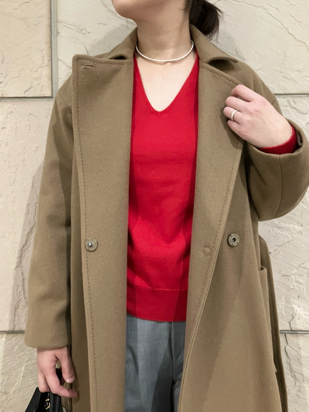 レッド系のニット/セーター、ベージュ系のその他アウター、グレー系のパンツを着用したレディースの秋コーディネートの2枚目の写真