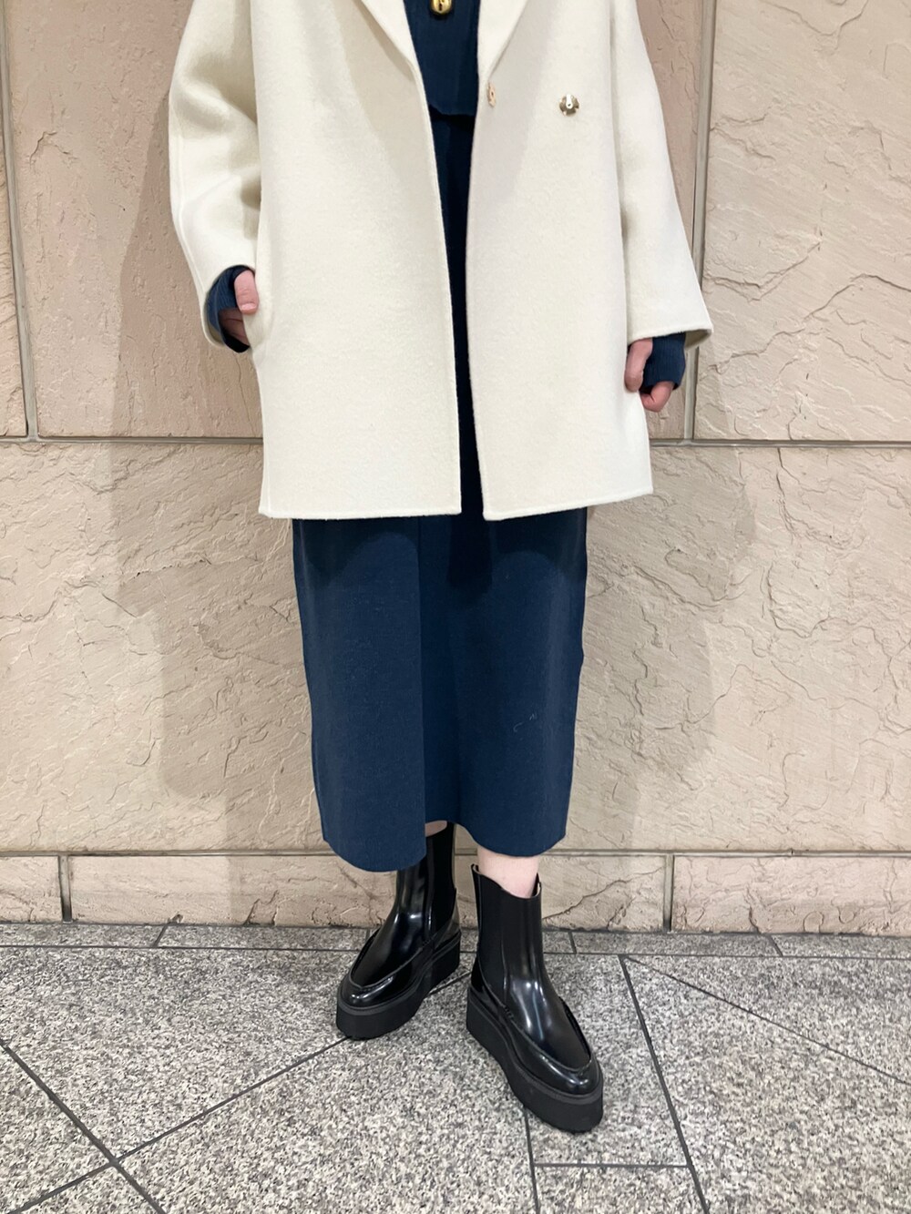 ホワイト系のチェスターコート、ブルー系のワンピース、ブラック系のブーツを着用したレディースの冬コーディネートの5枚目の写真