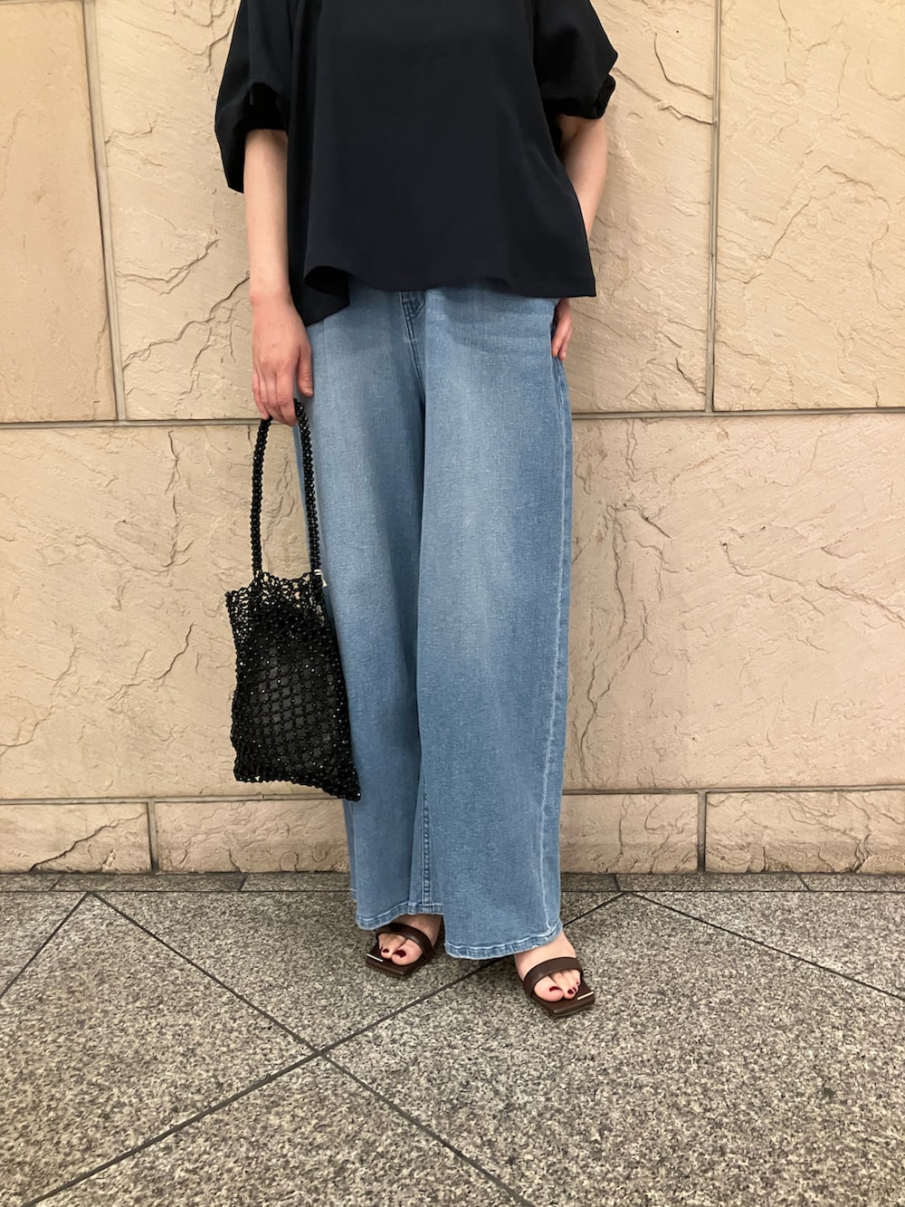 ブルー系のシャツ/ブラウス、ブラック系のハンドバッグ、ブルー系のデニムパンツを着用したレディースの夏コーディネートの4枚目の写真