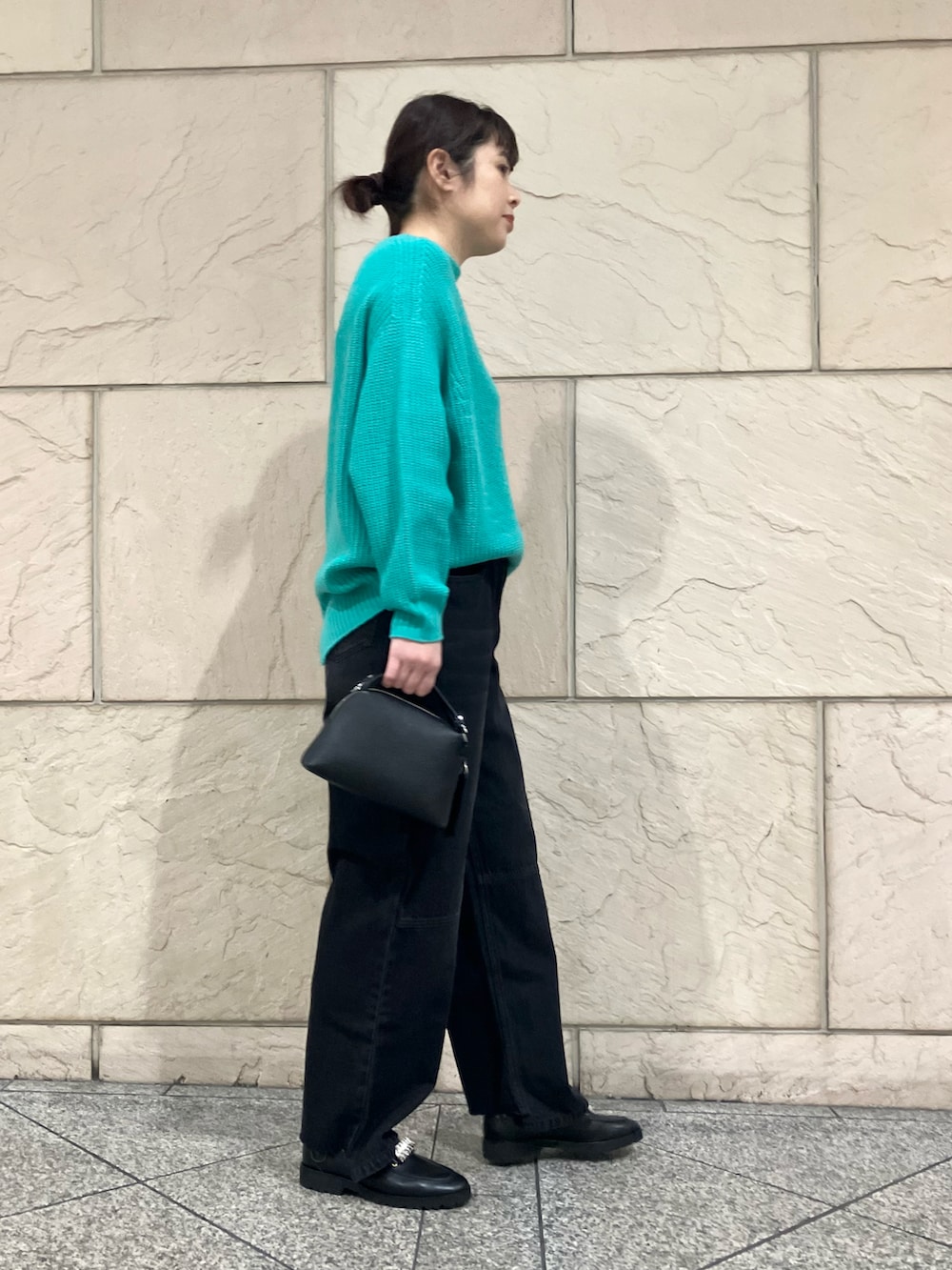 グリーン系のニット/セーター、ブラック系のデニムパンツ、ブラック系のショルダーバッグを着用したレディースの冬コーディネートの2枚目の写真