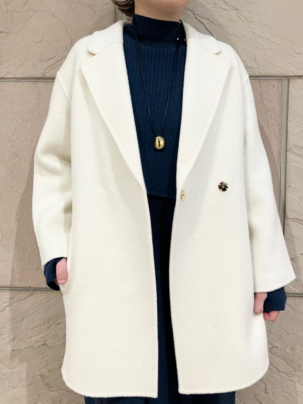 ホワイト系のチェスターコート、ブルー系のワンピース、ブラック系のブーツを着用したレディースの冬コーディネートの4枚目の写真