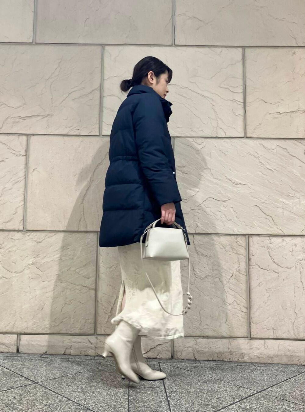 ベージュ系のブーツ、ブルー系のダウンジャケット/コート、オレンジ系のニット/セーターを着用したレディースの冬コーディネートの2枚目の写真