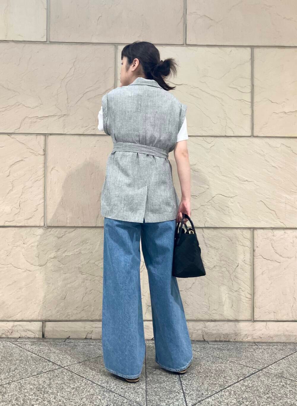 ブラック系のベスト、ブルー系のデニムパンツ、ホワイト系のTシャツ/カットソーを着用したレディースの春コーディネートの2枚目の写真