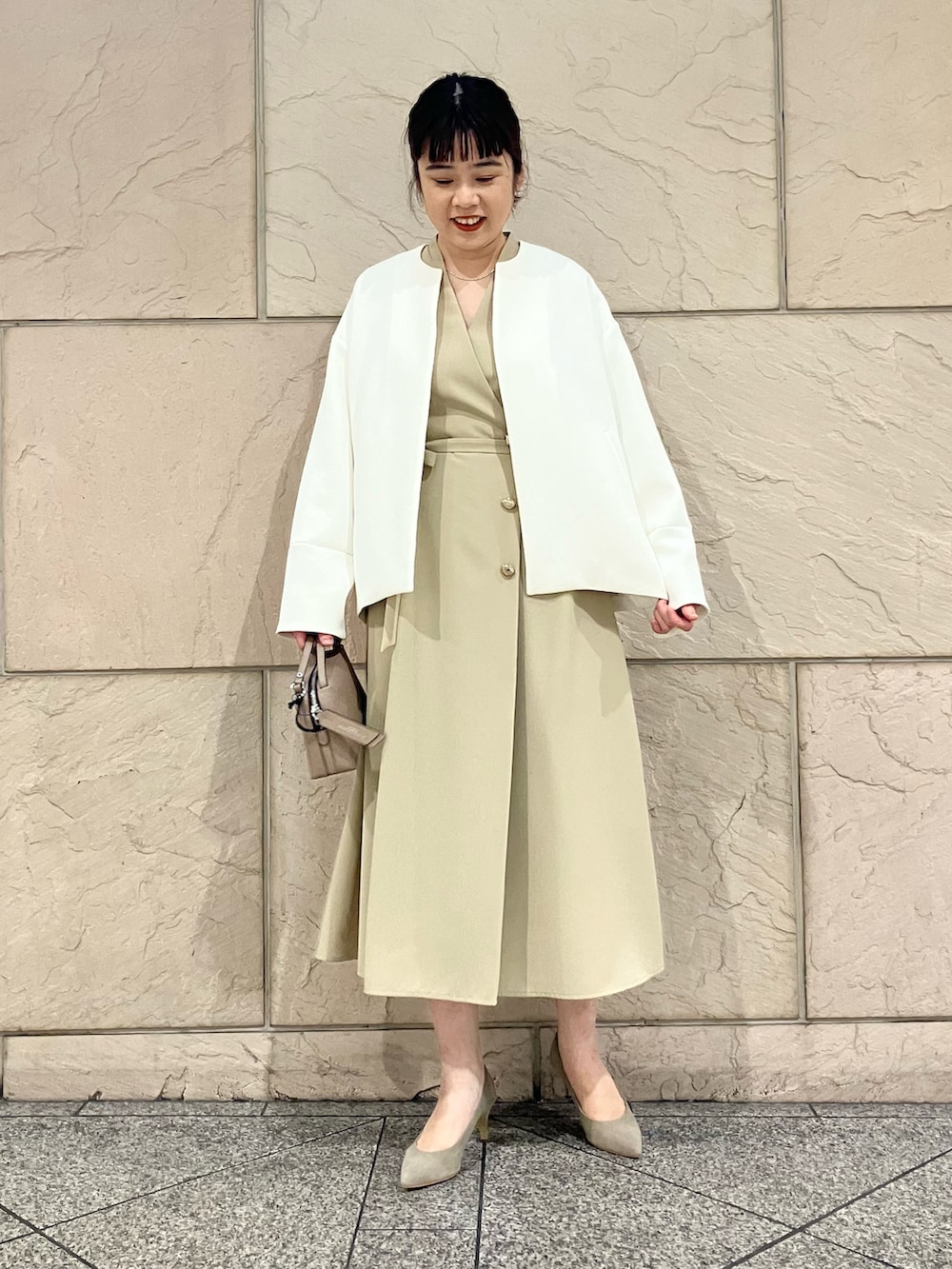 ベージュ系のワンピース、ブラウン系のパンプス、ホワイト系のノーカラージャケットを着用したレディースの冬コーディネートの4枚目の写真