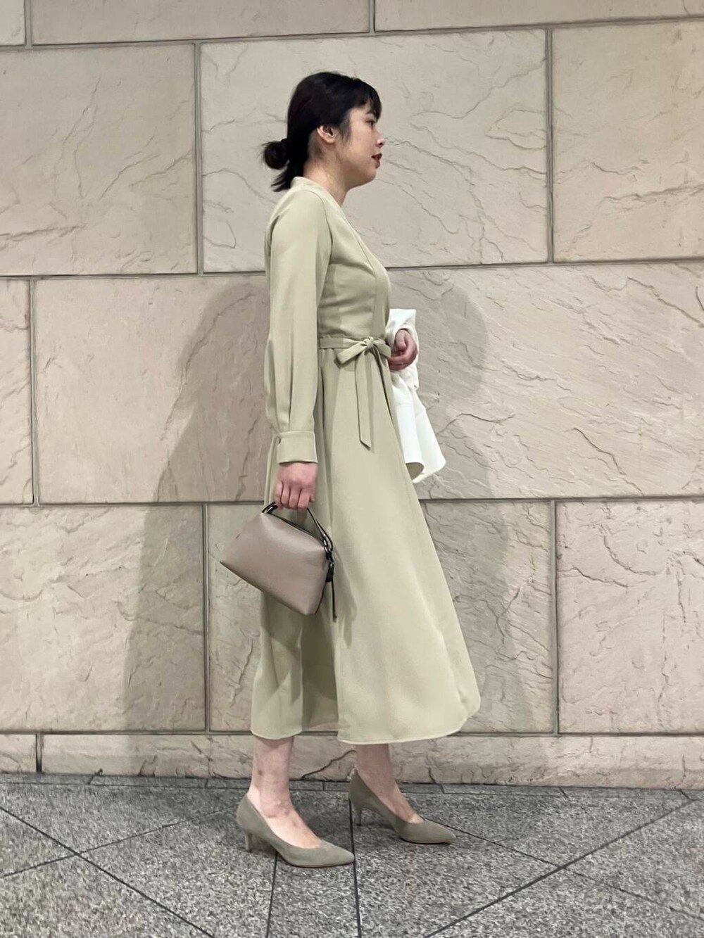 ブラウン系のパンプス、ホワイト系のノーカラージャケット、ベージュ系のワンピースを着用したレディースの冬コーディネートの3枚目の写真