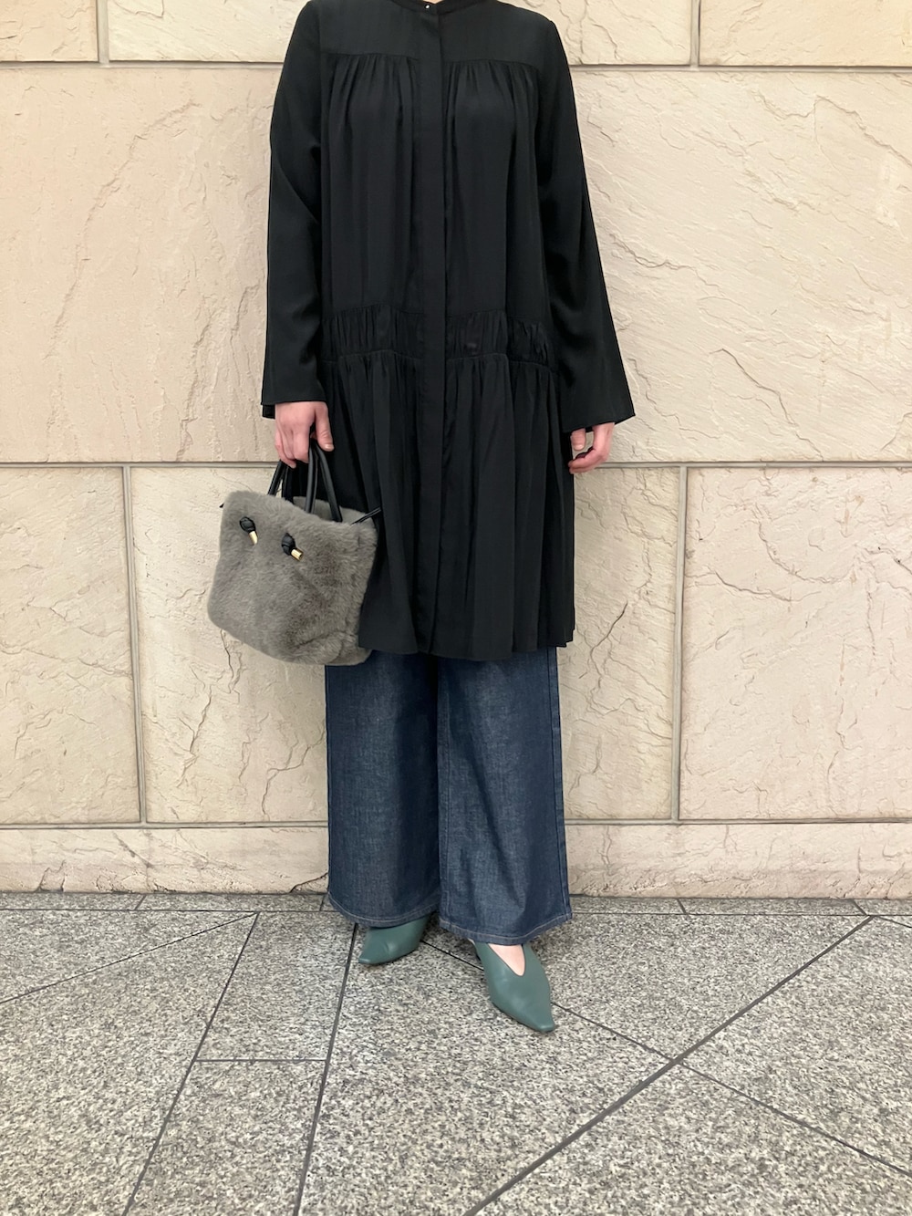 ブラック系のワンピース、ブラウン系のハンドバッグ、ブルー系のデニムパンツを着用したレディースの秋コーディネートの5枚目の写真