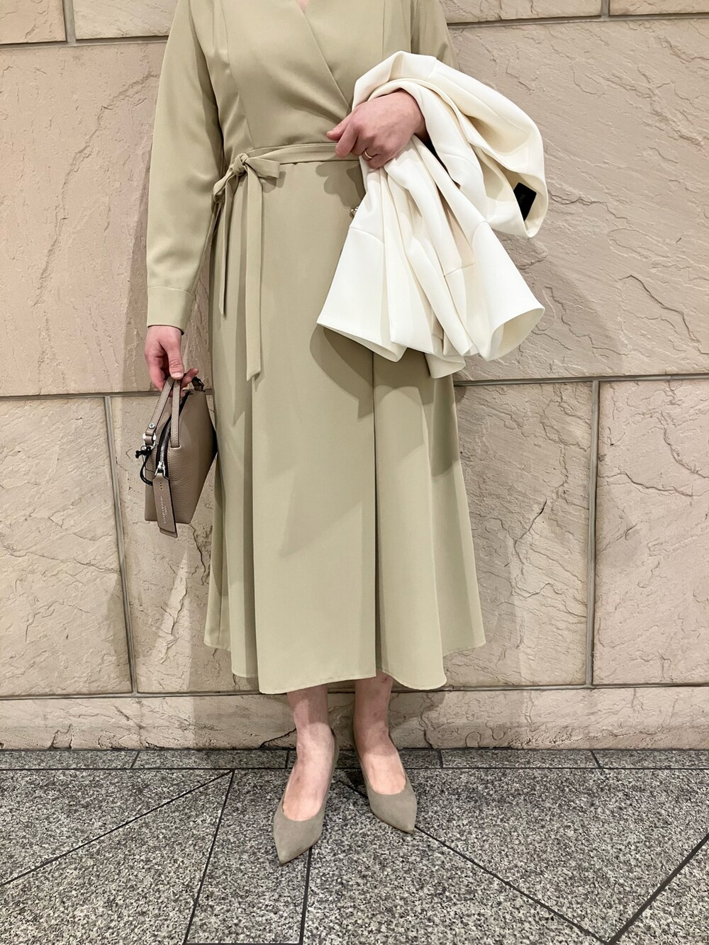 ベージュ系のワンピース、ブラウン系のパンプス、ホワイト系のノーカラージャケットを着用したレディースの冬コーディネートの3枚目の写真