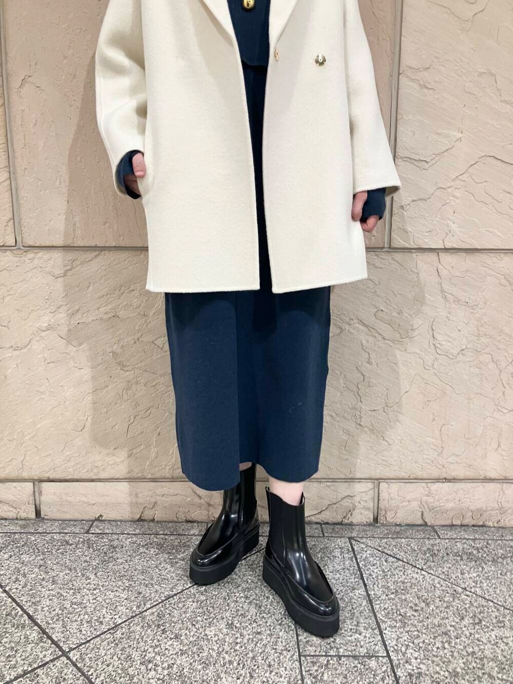 ホワイト系のチェスターコート、ブルー系のワンピース、ブラウン系のショルダーバッグを着用したレディースの冬コーディネートの5枚目の写真