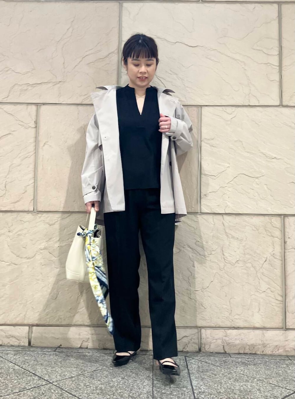 ブラック系のパンプス、ベージュ系のトレンチコート、ホワイト系のハンドバッグを着用したレディースの春コーディネートの2枚目の写真